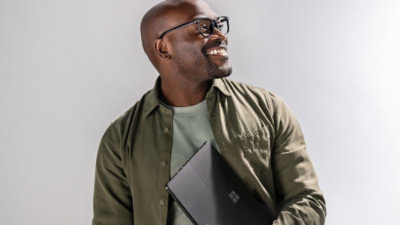 Person holding laptop against plain background