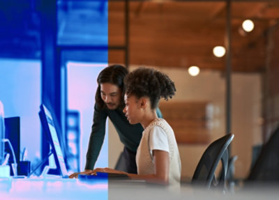 Two employees working on a computer while one is standing