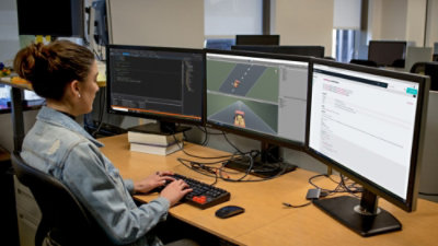 Person working at a desk with multiple computer monitors displaying dashboards and maps.
