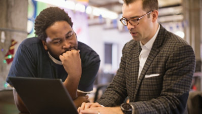 Two men using a laptop