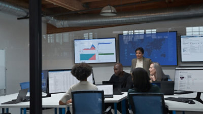 People in a security operations center with tech on monitors surrounding them