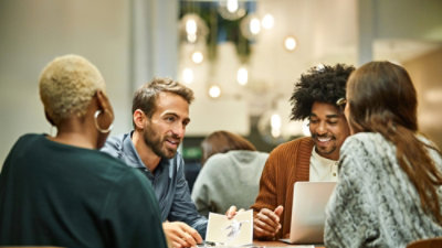A group of people sitting around a table with laptops and other items.