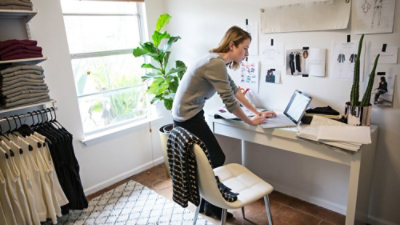 Person working on laptop at home studio desk.