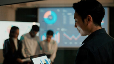 Man using a laptop with a screen of statistics behind him