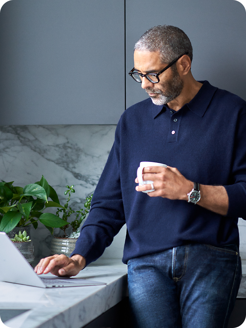 A man holding cup and using laptop.