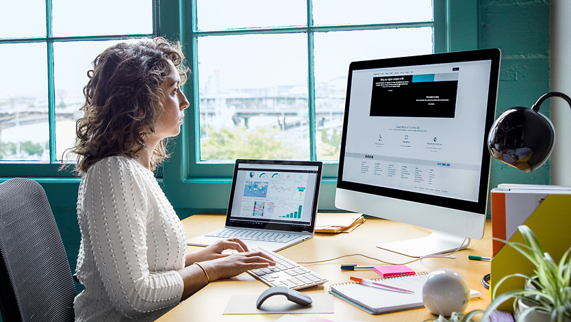 A woman works on a Surface Studio 2