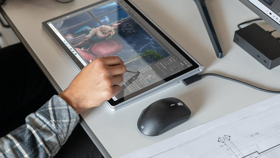 A person uses Surface Dock 2 to charge a Surface device and connect to a monitor.