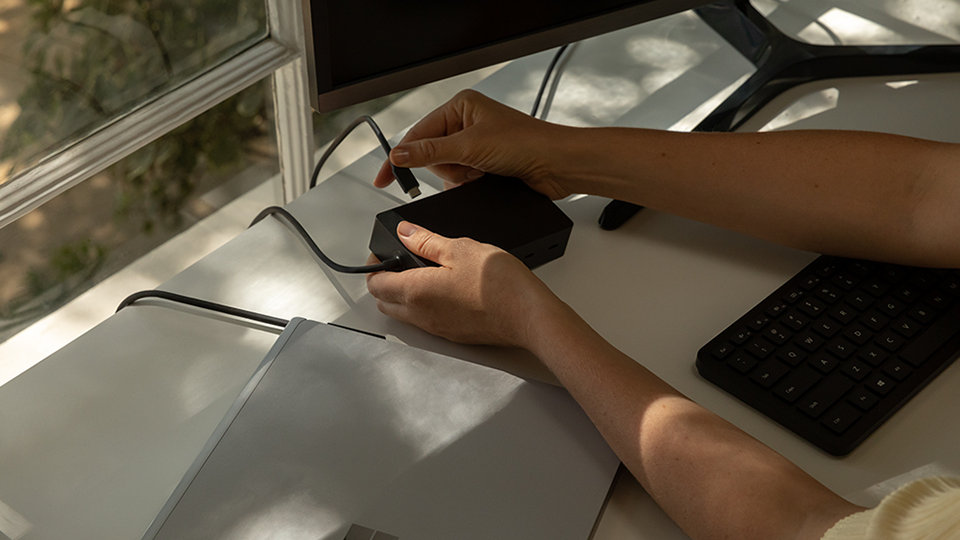 A person connects Surface Dock 2 for Business to a Surface device.