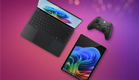 Ein Notebook, Tablet und Controller von Microsoft vor einem pinken Hintergrund.