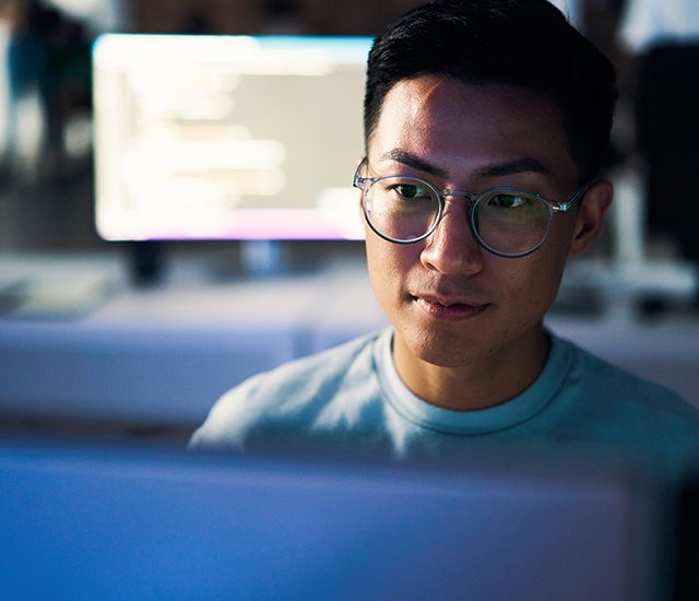 A man with glasses is looking thoughtfully, showcasing a focused expression and a sense of contemplation.