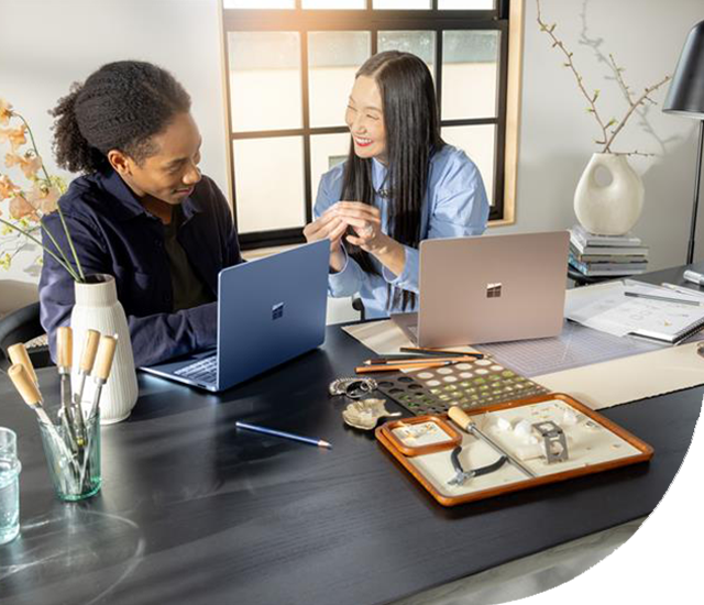 Surface photography of adult female and male inside using Surface Laptop (7th edition)  Copilot + PC in Sapphire and Dune.