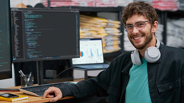 engaged developer portrait in the context of retail, warehouse with screen showing data.