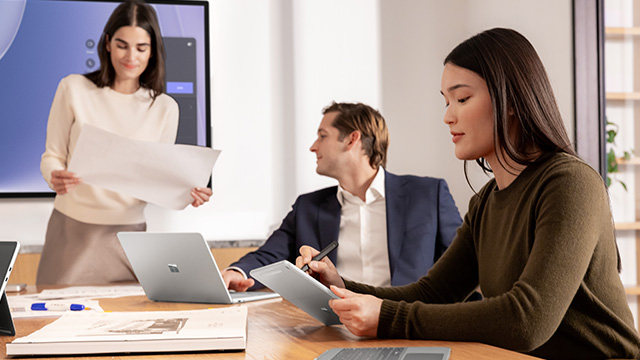 photograph of three executives at a conference table.