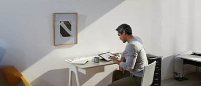 Una persona seduta al tavolo di una stanza luminosa con un'opera d'arte astratta sulla parete.