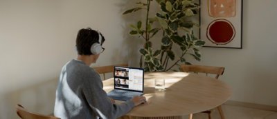 A person wearing headphones sitting at a table with a computer