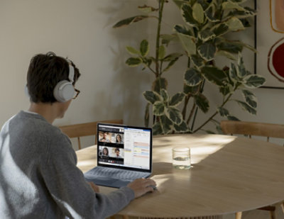 A man wearing headphones sitting at a table with a laptop.