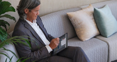A person sitting on a couch using a tablet and pen.