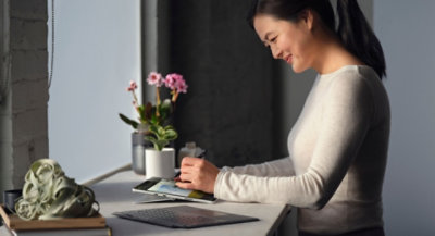 A person smiling using a pen and tablet.