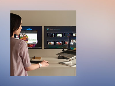 A person wearing a pink shirt standing in front of a computer screen.