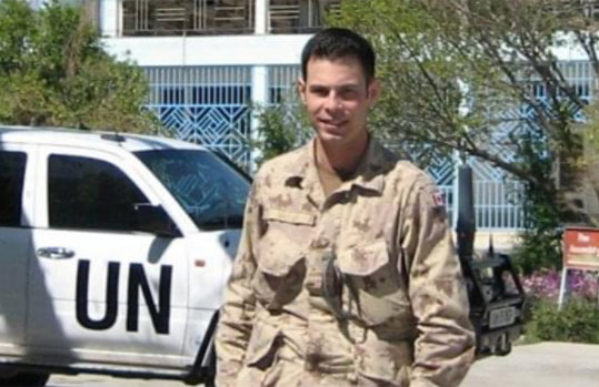 Scott Savage in a military uniform in front of a UN pickup truck 