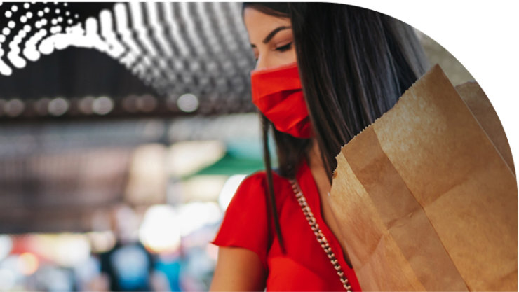 Woman wearing a face mask and carrying paper grocery bag