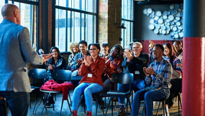 Audience clapping for inspirational speaker at business seminar.