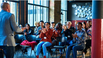 Audience clapping for inspirational speaker at business seminar.