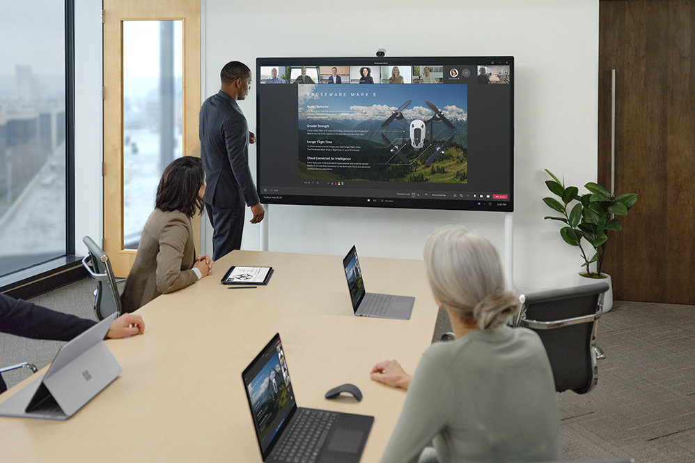 Meeting with people displaying Surface Hub 2 Camera above the screen which contains a screen image of a drone	