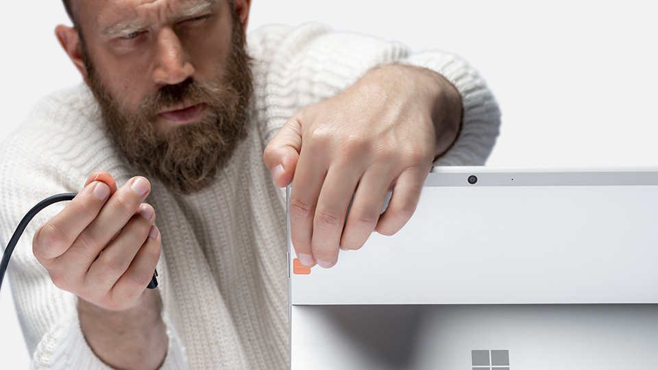 Een persoon die Surface Adaptive Kit-stickers aanbrengt op een Surface-apparaat.