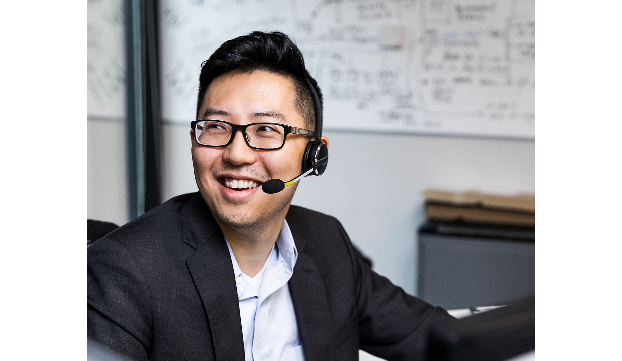 A person wearing spectacle smiling and using headphones