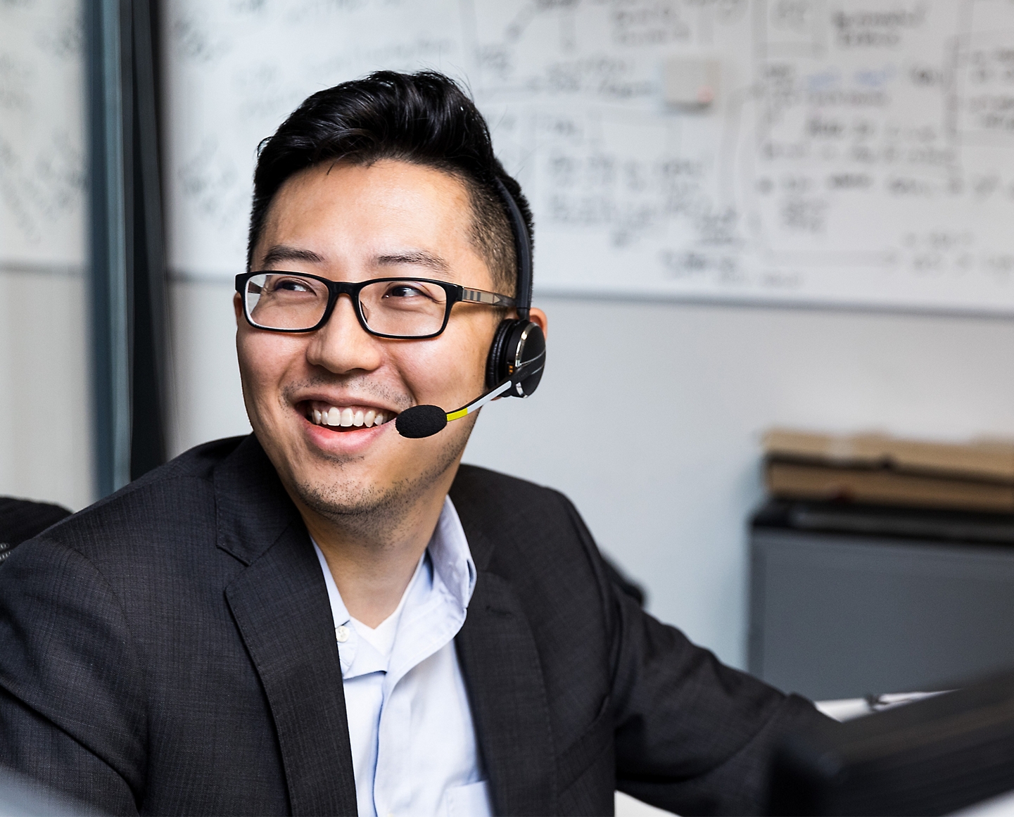 A person wearing spectacle smiling and using headphones