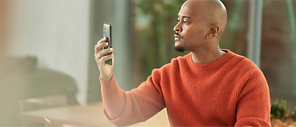 Egy férfi fényképet készít a mobiltelefonján.