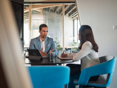 A man in a suit sitting at a table talking to a woman