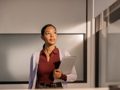 Professional holding a tablet and documents in an office setting.
