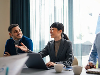Two colleagues collaborating at a table with a laptop during a meeting.