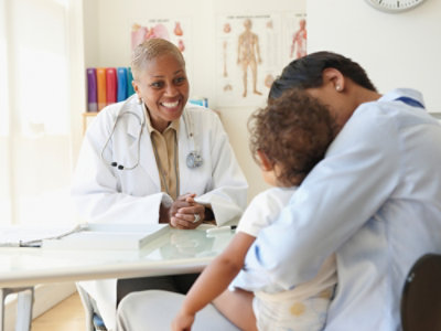 A doctor in a white coat talking to a child.
