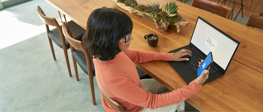 Žmogus sėdi prie stalo ir naudojasi kompiuteriu