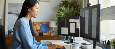 A woman working with multiple screens
