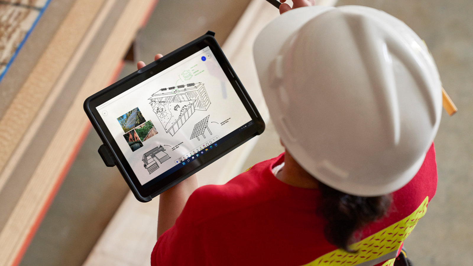 Une personne portant un casque de sécurité utilise une Surface Go 4 pour les entreprises sur un chantier, suggérant la facilité d’utilisation en déplacement de l’appareil.