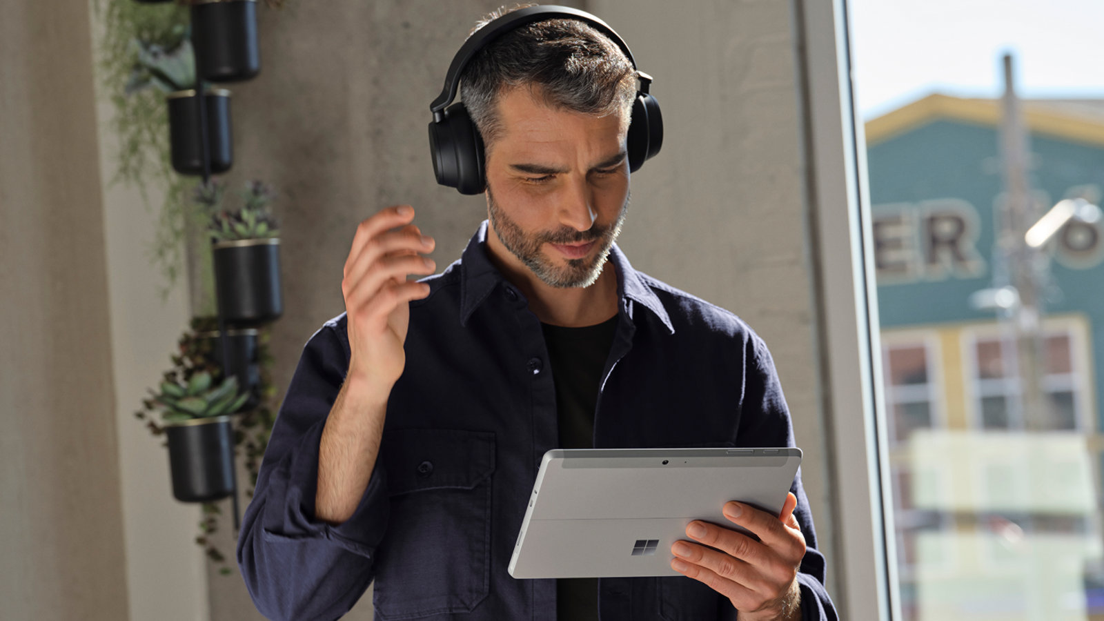 A person wearing headphones uses a Surface Go 4 for Business to take a video call.