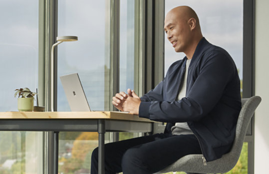 A person smiles while using Surface Laptop Go 3 for Business to take a video call, suggesting the benefits of the speakers and mics on Surface Laptop Go 3 for Business.