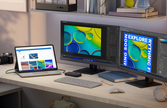 At a desk, a Surface Laptop Studio 2 for Business is connected to two additional displays and other various accessories, representing some of the accessories that Surface Laptop Studio 2 for Business can connect to. 