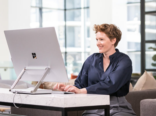 Une personne utilise Surface Studio 2+ pour les entreprises pour travailler sur un bureau debout.