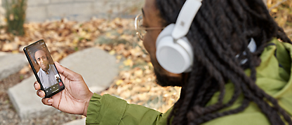 A person wearing headphones watching mobile
