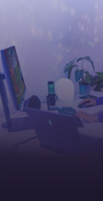 Gaming setup with a monitor, laptop, microphone, keyboard, and mouse on a desk, featuring ambient lighting and a purple gradient overlay.