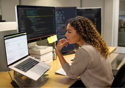 A woman sitting at a desk looking at a computer screen.