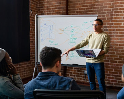 A man standing in front of a whiteboard pointing at something.