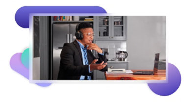 A person sitting at a kitchen island wearing over-the-ear headphones and participating in a call on their laptop.