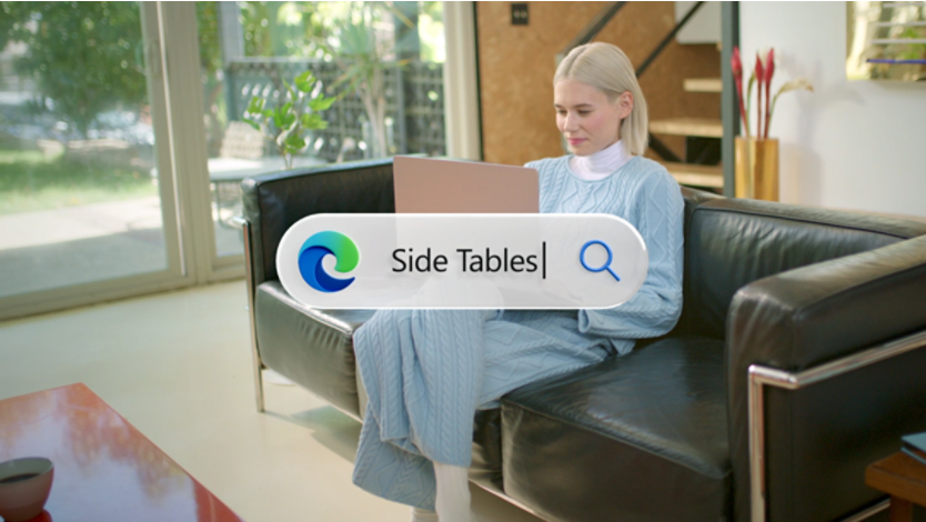 A person holding a computer on their lap while sitting on a couch. In the center of the image is a search bar with the Edge icon on the left and the search bar text reads Side Tables