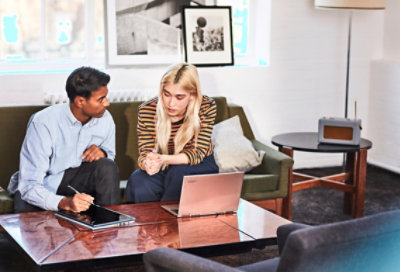 Δύο άτομα κάθονται σε έναν καναπέ και εργάζονται μαζί. Ο ένας χρησιμοποιεί tablet και πένα, και ο άλλος χρησιμοποιεί φορητό υπολογιστή